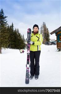 Beautiful smiling woman posing on top of slope with skis