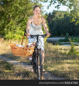 Beautiful smiling woman riding bicycle by the river