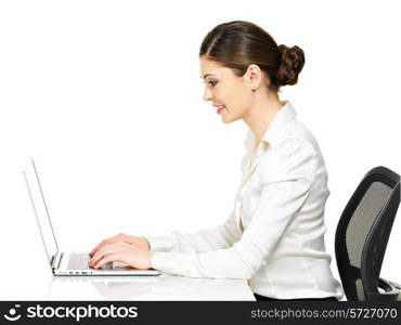 Beautiful smiling woman sits from the table and working on laptop in white shirt - isolated on white. &#xA;