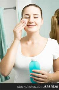 Beautiful smiling woman using moisturizing lotion at bathroom