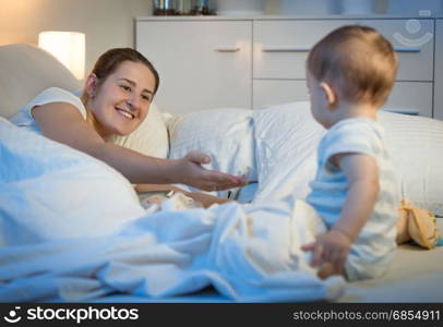 Beautiful smiling woman with baby in bed at night