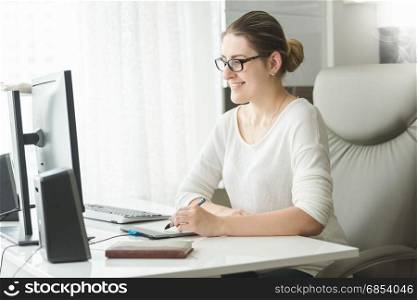 Beautiful smiling woman working at computer in home office