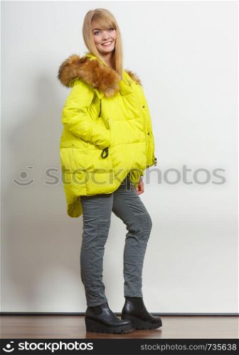 Beautiful smiling young fashionable girl wearing jacket with hood. Fashion in winter time.