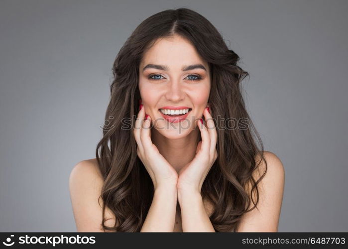 Beautiful smiling young woman. Beautiful smiling young woman stroking her clean beauty face