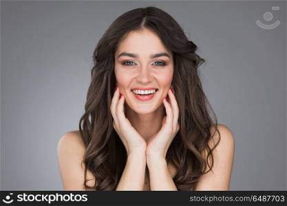 Beautiful smiling young woman. Beautiful smiling young woman stroking her clean beauty face