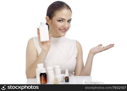 Beautiful smiling young woman showing a pill bottle and holding pills on the palm