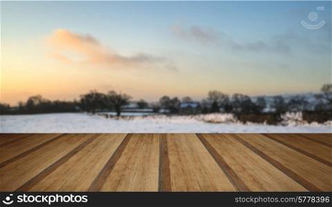 Beautiful snow covered sunrise Winter countryside landscape with wooden planks floor