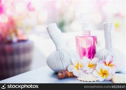 Beautiful spa or wellness treatment and product with compress balls, lotion, frangipani flower at spring or summer nature background, front view