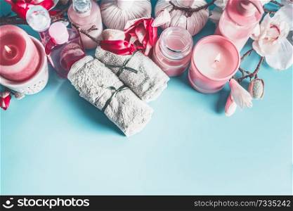 Beautiful spa setting with towels, flowers, candles and body care cosmetics at light blue background, top view with copy space. Beauty concept