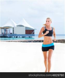 Beautiful sportive female running on the beach, workout on luxury Maldives resort, doing fitness exercise outdoors, healthy lifestyle, active summer vacation concept
