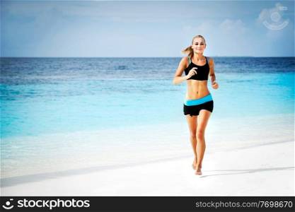 Beautiful sportive woman running along beautiful sandy beach, healthy lifestyle, enjoying active summer vacation near the sea