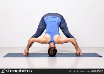 Beautiful sporty fit woman practices Ashtanga Vinyasa yoga asana Prasarita padottanasana D - wide legged forward bend D. Sporty woman practices Ashtanga Vinyasa yoga asana