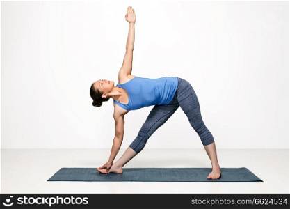 Beautiful sporty fit woman practices Ashtanga Vinyasa yoga asana utthita trikonasana - extended triangle pose. Woman practices yoga asana utthita trikonasana