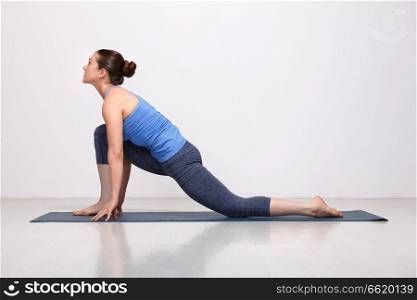 Beautiful sporty fit yogini woman practices yoga asana  Anjaneyasana - low crescent lunge pose in surya namaskar in studio. Fit yogini woman practices yoga asana  Anjaneyasana