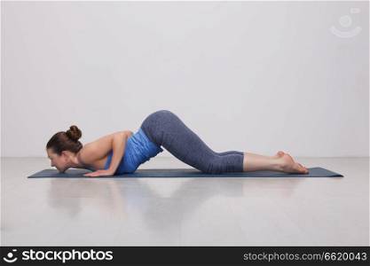 Beautiful sporty fit yogini woman practices yoga asana Ashtangasana - eight-limbed pose in studio. Sporty fit yogini woman practices yoga asana Ashtangasana
