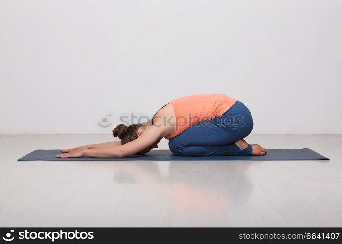 Beautiful sporty fit yogini woman practices yoga asana balasana (child&rsquo;s pose) - resting pose or counter asana for many asanas in studio. Beautiful sporty fit yogi girl practices yoga asana balasana
