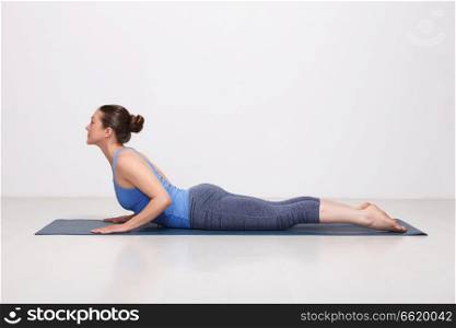 Beautiful sporty fit yogini woman practices yoga asana bhujangasana - cobra pose beginner variation in studio. Sporty fit yogini woman practices yoga asana bhujangasana