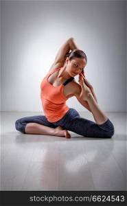 Beautiful sporty fit yogini woman practices yoga asana Eka pada rajakapotasana - one-legged pigeon pose in studio. Sporty fit girl practices yoga asana Eka pada kap