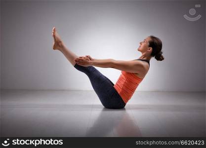 Beautiful sporty fit yogini woman practices yoga asana Paripurna navasana - boat pose. Woman practices yoga asana Plenary navasana