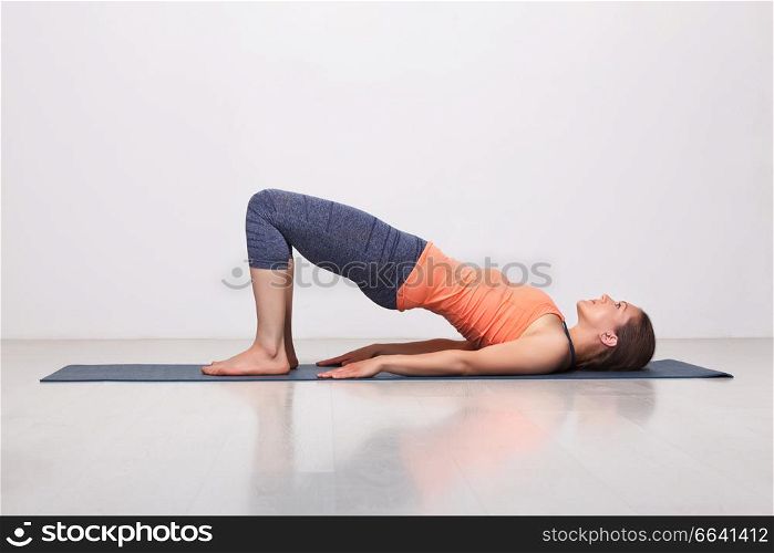 Beautiful sporty fit yogini woman practices yoga asana setu bandhasana - bridge pose beginner variation in studio. Beautiful sporty fit yogi girl practices yoga asana setu bandhas