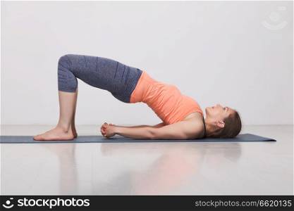 Beautiful sporty fit yogini woman practices yoga asana setu bandhasana - bridge pose variation in studio. Beautiful sporty fit yogi girl practices yoga asana setu bandhas