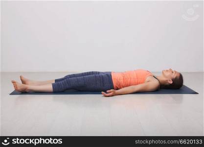 Beautiful sporty fit yogini woman relaxes in yoga asana Savasana - corpse pose in studio. Beautiful sporty fit yogi girl relaxes in yoga asana Savasana