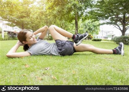 Beautiful sporty woman is doing exercises in green park