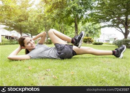 Beautiful sporty woman is doing exercises in green park