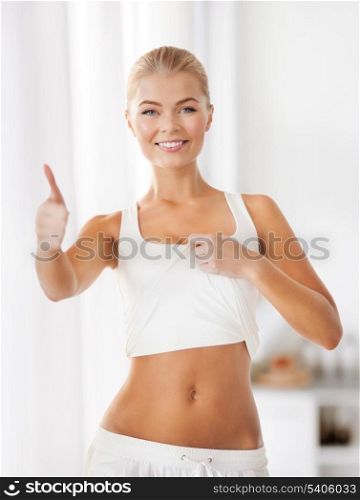 beautiful sporty woman showing thumbs up and her abs