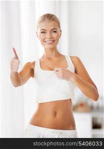 beautiful sporty woman showing thumbs up and her abs