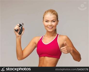 beautiful sporty woman with hand expander showing thumbs up