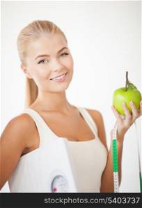 beautiful sporty woman with scale, green apple and measuring tape