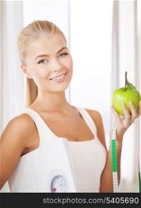 beautiful sporty woman with scale, green apple and measuring tape