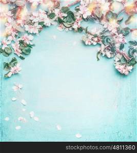 Beautiful spring nature background with lovely blossom, petal and bokeh on turquoise blue background , top view, frame. Springtime concept