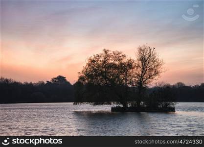 Beautiful Spring sunrise over calm lake in English countryside