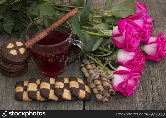 beautiful still life from roses, cookies and tea on a wooden table