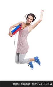 Beautiful student jumping with books and headphones, isolated over a white background