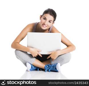 Beautiful student smiling and sitting in the floor with a laptop, isolated over a white background