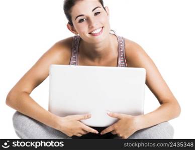 Beautiful student smiling and sitting in the floor with a laptop, isolated over a white background
