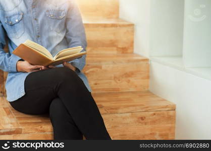 Beautiful student woman sitting at the stair and reading a book