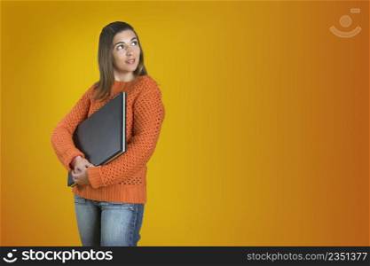 Beautiful student woman with a laptop over a yellow background