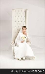 Beautiful studio shot of elegant bride posing at luxurious chair