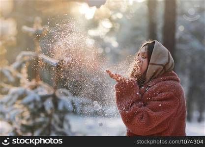 Beautiful, stylish and young girl, blowing the snow from her hands in winter forest. Christmas holiday. Beautiful, stylish and young girl, blowing the snow from her hands in winter forest. Christmas holiday.