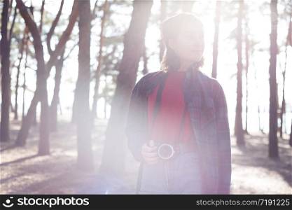beautiful stylish girl holding a camera in the forest at sunset time