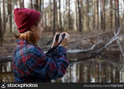 beautiful stylish girl holding a camera in the forest. wild conditions