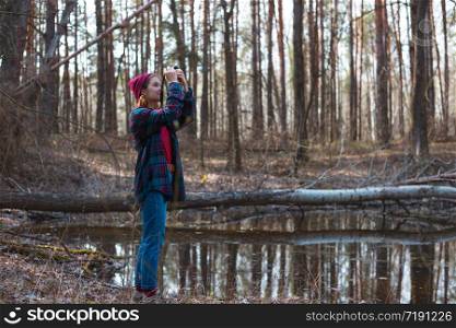 beautiful stylish girl holding a camera in the forest. wild conditions
