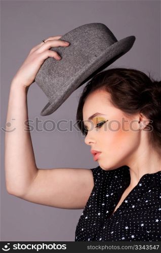 Beautiful stylish young woman with full makeup posing with hat.