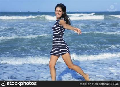 Beautiful summer brunette girl jumping on the blue beach
