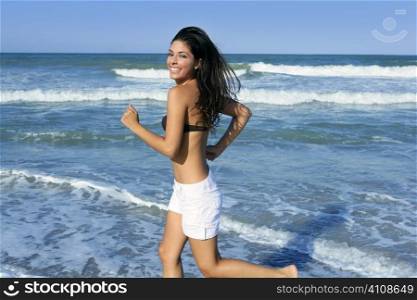 Beautiful summer brunette girl jumping on the blue beach