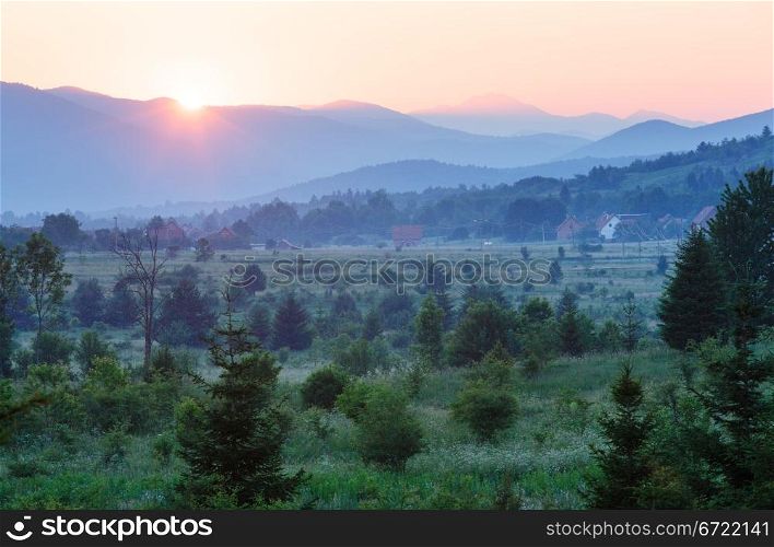 Beautiful summer country landscape with setting sun over mountains
